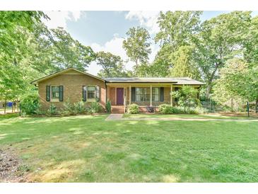 Charming brick home featuring a well-manicured front lawn and inviting front porch at 308 Rainbow Dr, Carrboro, NC 27510