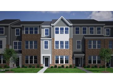 Charming new construction townhome with a brick and gray siding exterior and professionally landscaped front yard at 323 Chesapeake Cmns St # 104, Garner, NC 27529