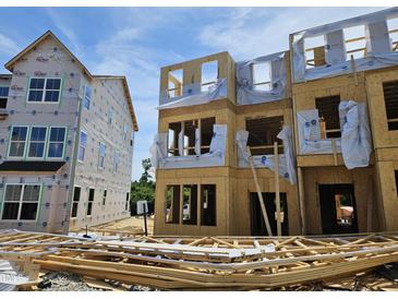 A new construction home with exposed framing, sheathing, and stacked lumber, ready for the next phase of building at 335 Chesapeake Cmns St # 107, Garner, NC 27529