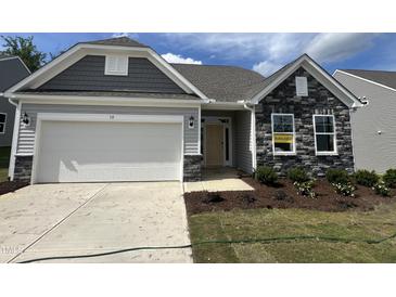 Charming home featuring a two-car garage, stone accents, light gray siding and well-maintained landscaping at 38 Gander Dr, Benson, NC 27504