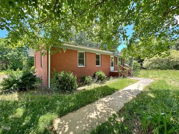Charming single-story brick home with inviting front entrance and lush surrounding greenery at 80 Dunn Rd, Louisburg, NC 27549