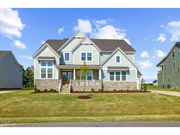 Beautiful two-story home featuring stone accents, light blue siding, and a welcoming front porch at 8416 Brady Pointe Rd, Fuquay Varina, NC 27526
