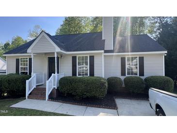 Inviting single-story home featuring fresh neutral siding, dark shutters, a well-manicured front lawn, and a cozy entryway at 106 Grange Dr, Wendell, NC 27591