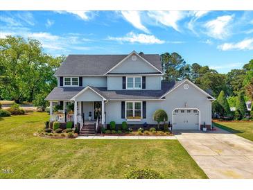 Charming two-story home with attached garage, well-manicured lawn, and inviting front porch at 128 Christy Ln, Dunn, NC 28334