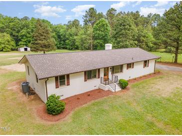 Beautifully landscaped ranch-style home with a lush green lawn and mature trees in a serene setting at 2712 Nc 57, Hillsborough, NC 27278
