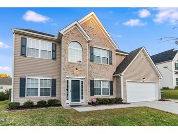 Charming two-story home features a brick facade, blue shutters, landscaped yard, and an attached two-car garage at 2902 Framer Ln, Durham, NC 27704