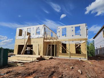 Two-story home under construction featuring wood framing, sheathing, and house wrap, set against a clear blue sky at 3007 Dog Rose Dr # 174, Durham, NC 27703