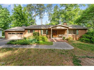 Charming brick home with a covered front porch and lush landscaping at 4017 Huckleberry Dr, Raleigh, NC 27612