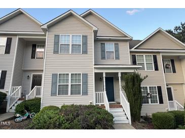 Charming townhome featuring gray siding, blue shutters, a quaint front porch, and a tidy, landscaped yard at 407 Whitehall Ct, Clayton, NC 27520