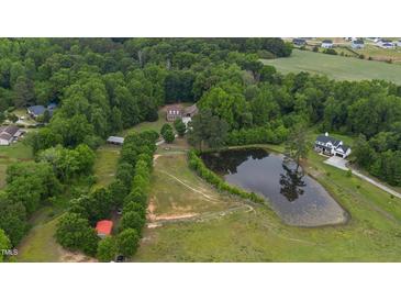 Expansive aerial view of estate featuring a large pond, fenced pastures, lush trees, and multiple outbuildings at 5237 Christian Light Rd, Fuquay Varina, NC 27526