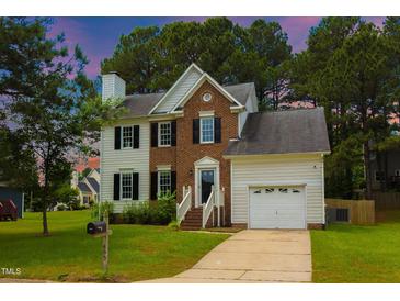 Charming two-story home with a brick facade, white siding, a well-manicured lawn and an attached garage at 805 Penncross Dr, Raleigh, NC 27610