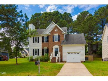 Charming two-story home with brick and white siding, attached garage, and a well-manicured front yard with mature trees at 805 Penncross Dr, Raleigh, NC 27610