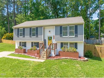 Charming split-level home featuring a vibrant yellow front door and well-maintained lawn at 1220 Sherbrooke Ct, Raleigh, NC 27612