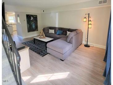 Living room with a large sectional sofa, decorative lighting, and modern decor that create an inviting atmosphere at 141 Jones Franklin Rd # E, Raleigh, NC 27606