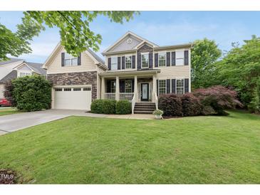Charming two-story home featuring a landscaped front yard and a welcoming front porch with stone and siding accents at 1612 Rainesview Ln, Apex, NC 27502