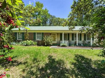 Charming single-story home with a well-manicured lawn and a welcoming front porch and green shutters at 305 Reynolds N Ave, Durham, NC 27707