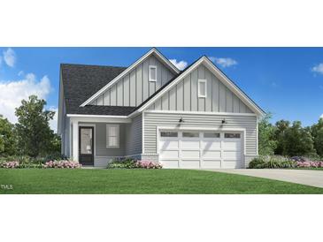 Charming home featuring a two-car garage, gray siding, black front door, and attractive landscaping at 5228 Bowes Meadow Ct # 15, Raleigh, NC 27610