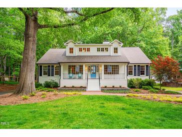 Charming traditional home featuring a bright blue door, white facade, landscaped yard, and welcoming front porch at 823 Churchill Dr, Chapel Hill, NC 27517