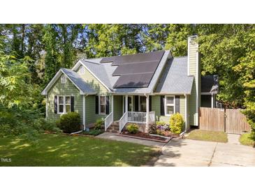 Charming green home with gray roof, black shutters, solar panels, manicured lawn, and appealing curb appeal at 909 Alderleaf Dr, Fuquay Varina, NC 27526