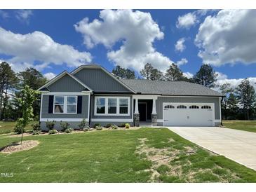 Charming single-story home with a manicured lawn and a two-car garage on a sunny day at 158 Sourgum Ct, Zebulon, NC 27597