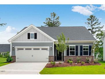 Charming single-story home with a two-car garage, a manicured lawn, and brick accents at 2021 Clydner Dr, Apex, NC 27523