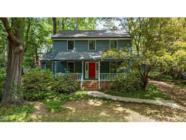 Charming two-story home with a welcoming porch and vibrant red front door surrounded by lush landscaping at 522 Lochness Ln, Cary, NC 27511
