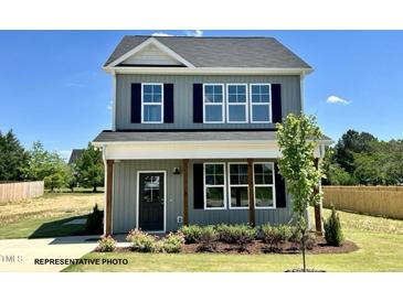Charming two-story home with blue siding, dark shutters, covered porch, and beautifully landscaped yard at 107 Legolas Ct, Middlesex, NC 27557