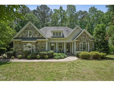 Charming stone-accented home with manicured lawn and lush landscaping creating great curb appeal at 2709 Penfold Ln, Wake Forest, NC 27587