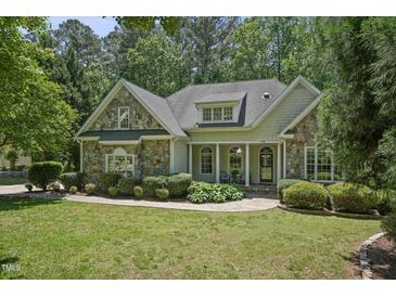 Charming stone and siding home with a well-manicured lawn and inviting front porch at 2709 Penfold Ln, Wake Forest, NC 27587
