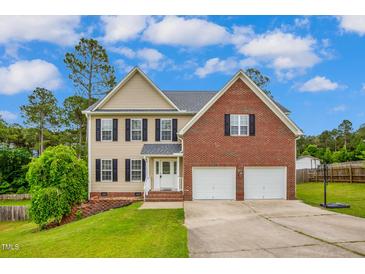 Charming two-story home featuring a brick and siding exterior, two-car garage, and well-manicured lawn at 32 Lattimore Rd, Cameron, NC 28326