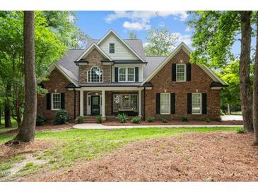 Stunning brick home with stone accents, dormer window, a welcoming porch and beautifully landscaped front yard at 5916 Two Pines Trl, Wake Forest, NC 27587
