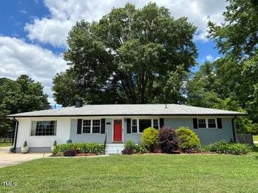 Charming single-story home featuring a manicured lawn, red front door, and lush landscaping at 704 S Mineral Springs Rd, Durham, NC 27703