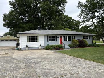 Charming single-story home featuring a red front door, well-maintained lawn, and a detached garage at 704 S Mineral Springs Rd, Durham, NC 27703