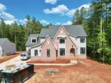 Newly built two-story home boasts gray siding, brick accents, black window trim and an arched entryway at 7932 Wexford Waters Ln, Wake Forest, NC 27587