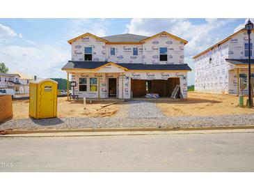 New home construction featuring Tyvek HomeWrap, located on a gravel lot with a portable toilet on site at 1124 Landen Creek Ln, Zebulon, NC 27597