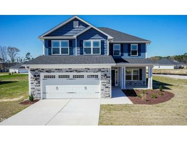 Charming two-story home boasts a striking blue exterior, complemented by a stone-accented garage and well-manicured landscaping at 301 New Twin Br Ct, Smithfield, NC 27577