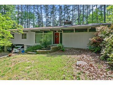 Charming single-story home with a red front door and well-maintained landscaping, nestled among mature trees at 4501 Zebulon Rd, Zebulon, NC 27597