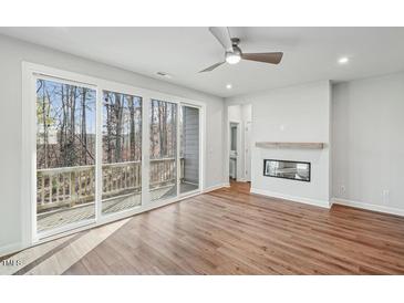 Bright living room with hardwood floors, ceiling fan, fireplace, and large sliding glass doors to the outside at 4607 Mint Leaf Ln, Raleigh, NC 27612