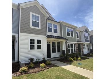 Charming townhome featuring a well-manicured lawn and a mix of siding, shingle, and stone architectural details at 6445 Granite Quarry Dr, Raleigh, NC 27610