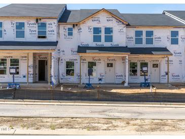 Unfinished new construction townhomes with black roof and Tyvek wrap ready for customization and personalization at 713 Chandler Stone Dr, Zebulon, NC 27597