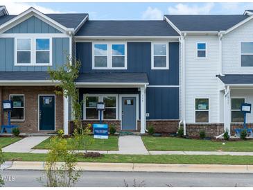 Attractive townhome featuring blue and white exterior, a well-maintained lawn, and a sidewalk at 715 Chandler Stone Dr, Zebulon, NC 27597