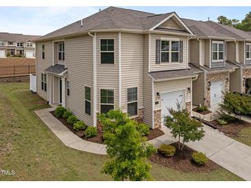 Two-story townhome features a one-car garage, neutral siding, manicured landscaping, and a concrete drive at 1136 Longitude Dr, Durham, NC 27713