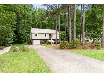 Split level home with beige siding, brick accents, metal roof, driveway, and mature landscaping at 5001 Simpson Dr, Sanford, NC 27330
