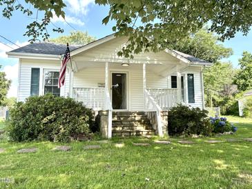 Charming home featuring a welcoming front porch, stone steps, lush landscaping, and traditional American flag at 6 First St, Franklinton, NC 27525