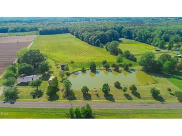 Aerial view of a property featuring a pond, fields, mature trees, and the home at 623 Chambers Rd, Rougemont, NC 27572