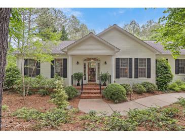 Charming home featuring a well-manicured lawn, black shutters, and brick stairs leading to the front door at 826 Rushing, Pittsboro, NC 27312