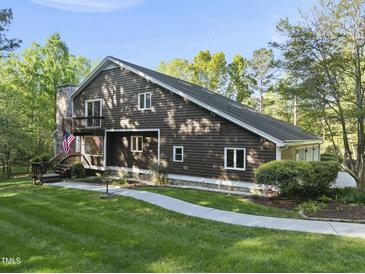 Two-story home showcasing a unique wood facade, balcony, and a stone chimney at 13 Crosswinds Estates Dr, Pittsboro, NC 27312
