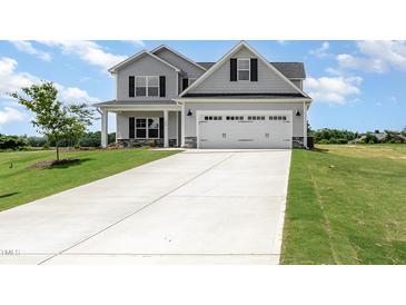 Charming two-story home featuring a gray exterior, attached garage, and a well manicured lawn at 188 Tuskeegee Dr, Smithfield, NC 27577