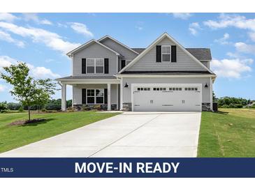 Charming two-story home features a manicured lawn, gray siding, and a bright white garage door with black hardware at 188 Tuskeegee Dr, Smithfield, NC 27577