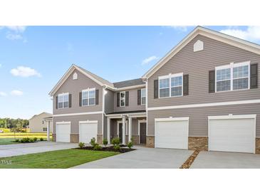 New construction townhomes with attached garages and manicured lawns on a sunny day at 236 Moyer Dr, Graham, NC 27253